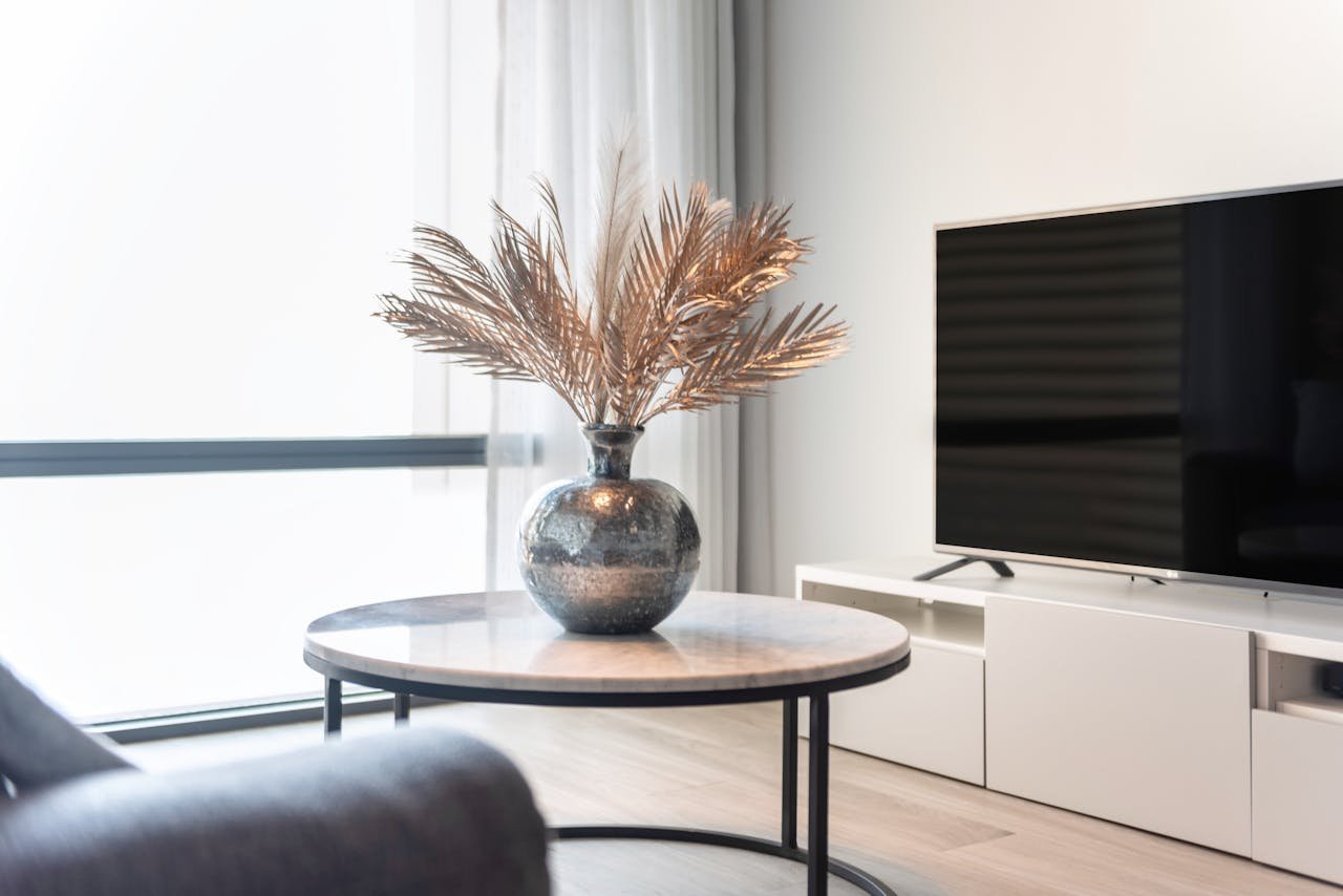 Stylish living room featuring a TV, table, and a vase with decorative leaves.